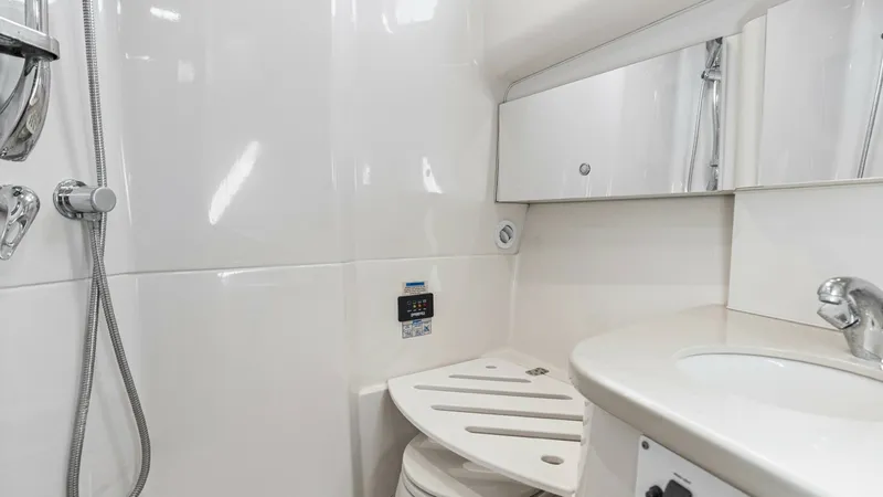 Slide: The Image of Modern Yacht Bathroom with Shower The bathroom on the 2006 Wellcraft 360 Coastal features a sleek and modern design with high-gloss white surfaces. Equipped with a compact shower area and a practical vanity with ample storage, it offers both functionality and style. The space is well-lit, - 6312507