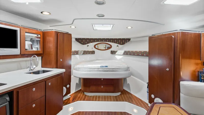 Slide: The Image of Spacious Interior Cabin View The interior cabin of the 2006 Wellcraft 360 Coastal 'Unbridled' features a luxurious layout with rich wooden cabinetry and flooring, creating a warm and inviting atmosphere. The central queen-sized berth is elegantly framed by stylish decor and ample sto - 6312499
