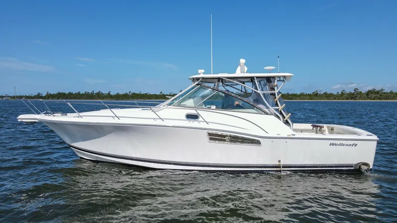 Slide: The Image of Profile View of 2006 Wellcraft 360 Coastal This image showcases the sleek profile of the 2006 Wellcraft 360 Coastal, known as 'Unbridled'. The vessel's streamlined design and sturdy construction are complemented by a spacious cockpit and protective hardtop. The clean lines and classic white hull r - 6312529