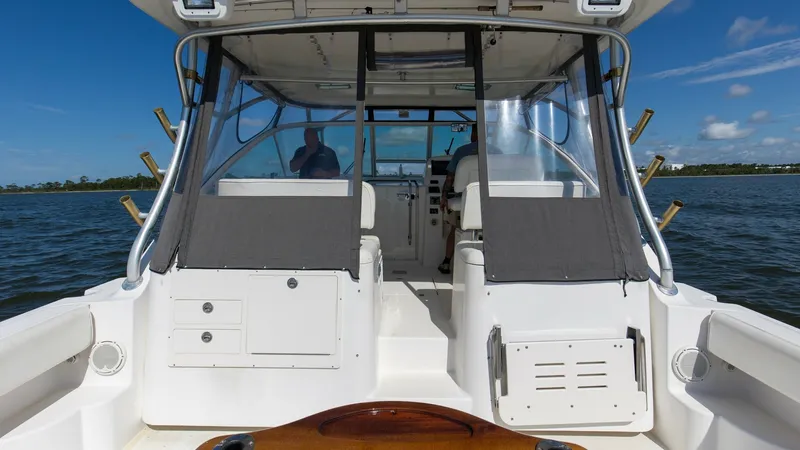 Slide: The Image of Aft Deck and Helm Enclosure The aft deck of the 2006 Wellcraft 360 Coastal features a spacious layout with a sturdy teak table, perfect for fishing or social gatherings. The helm is enclosed with clear panels, offering protection from the elements while maintaining visibility. The s - 6312501
