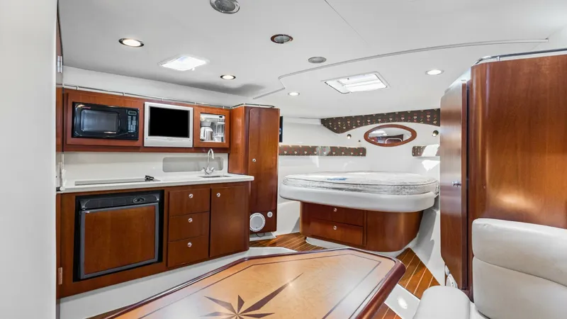 Slide: The Image of Elegant Interior Galley and Dinette The interior of the 2006 Wellcraft 360 Coastal 'Unbridled' features a beautifully appointed galley with rich wood cabinetry and modern appliances, including a microwave and sink. The adjacent dinette offers a stylish inlaid wood table, creating a comforta - 6312504