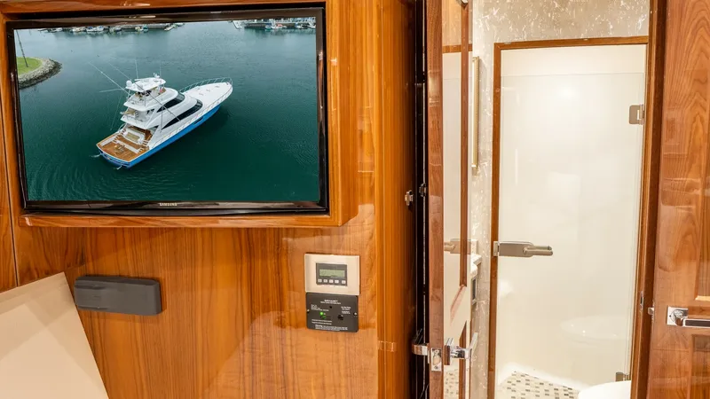 Slide: The Image of Guest Cabin with Ensuite Bathroom This elegant guest cabin on the Viking 92 Skybridge features rich wood paneling and a wall-mounted television for entertainment. The ensuite bathroom offers a modern glass-enclosed shower and sleek fixtures, providing comfort and convenience. The luxuriou - 6612525