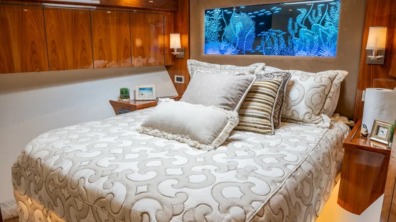 Slide: The Image of Luxurious Guest Stateroom This elegantly appointed guest stateroom on the 2020 Viking 92 Skybridge features a plush queen-sized bed with intricate bedding and ample storage. The rich wood paneling and ambient lighting create a warm and inviting atmosphere. A stunning backlit marin - 6612518