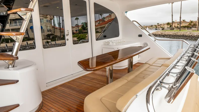 Slide: The Image of Aft Deck with Seating and Views The aft deck of the Viking 92 Skybridge features elegant teak flooring and a spacious seating area with plush cushions, perfect for socializing. A polished wooden table provides a sophisticated touch, ideal for dining al fresco while enjoying panoramic vi - 6612569