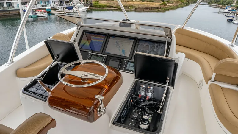 Slide: The Image of Skybridge Helm Station The helm station on the 2020 Viking 92 Skybridge features a sleek, polished wood steering wheel and advanced navigation displays. The layout provides excellent visibility and easy access to control panels, ensuring a smooth and efficient piloting experien - 6612576