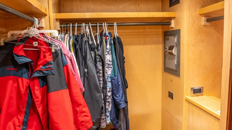Slide: The Image of Master Stateroom Walk-In Closet This spacious walk-in closet in the master stateroom of the 2020 Viking 92 Skybridge showcases ample hanging space and shelving for wardrobe essentials. The warm wood finishes provide a luxurious touch, complemented by a secure built-in safe for valuables - 6612545