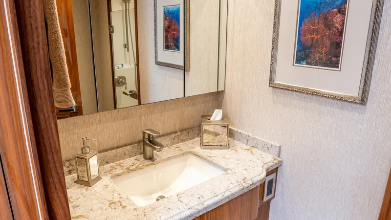 Slide: The Image of Elegant Guest Bathroom Vanity This image showcases the sophisticated guest bathroom on the Viking 92 Skybridge. The room features a sleek marble countertop with a modern rectangular sink and high-end fixtures. Warm wood cabinetry and tasteful wall art enhance the inviting atmosphere, - 6612519