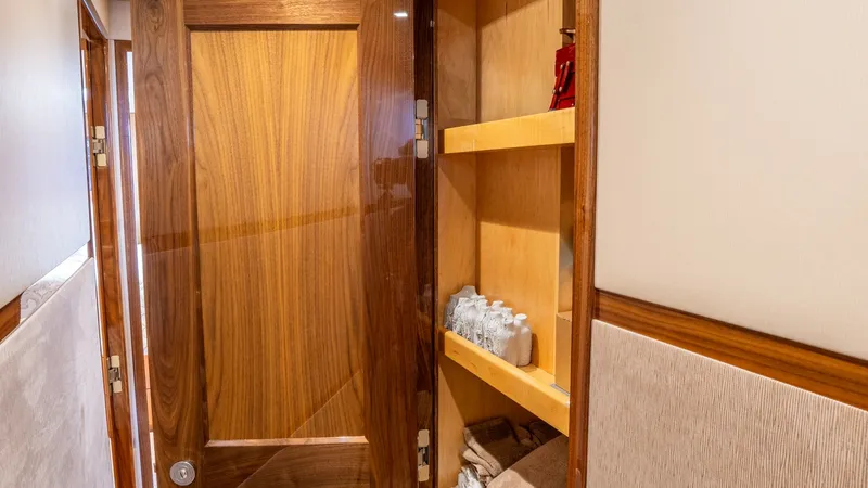 Slide: The Image of Hallway Linen Storage Area This image showcases the hallway linen storage on the Viking 92 Skybridge, featuring elegant wooden shelving. The open cabinetry offers ample space for towels and toiletries, accentuated by warm wood finishes that enhance the vessel's luxurious interior d - 6612562
