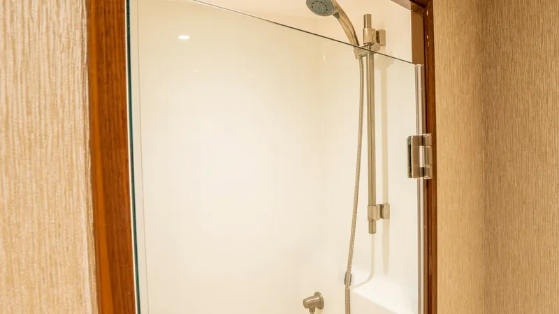 Slide: The Image of Elegant Enclosed Shower Stall This spacious shower stall features a sleek glass door and modern fixtures, providing a luxurious bathing experience aboard the Viking 92 Skybridge. The warm wood trim complements the contemporary design, while the soft lighting creates an inviting ambian - 6612520