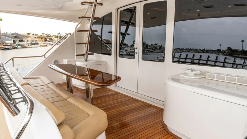 Slide: The Image of Aft Deck with Seating and Ladder The aft deck of the Viking 92 Skybridge features elegant teak flooring and comfortable seating, perfect for relaxation and entertaining. A sleek ladder provides easy access to the upper levels, while the glossy wooden table serves as a centerpiece for out - 6612568