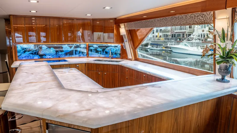 Slide: The Image of Elegant Salon Bar Area The spacious salon bar on the 2020 Viking 92 Skybridge features a stunning marble countertop and rich wood cabinetry, creating a luxurious ambiance. Large windows provide ample natural light and picturesque views, enhancing the sophisticated atmosphere. P - 6612514