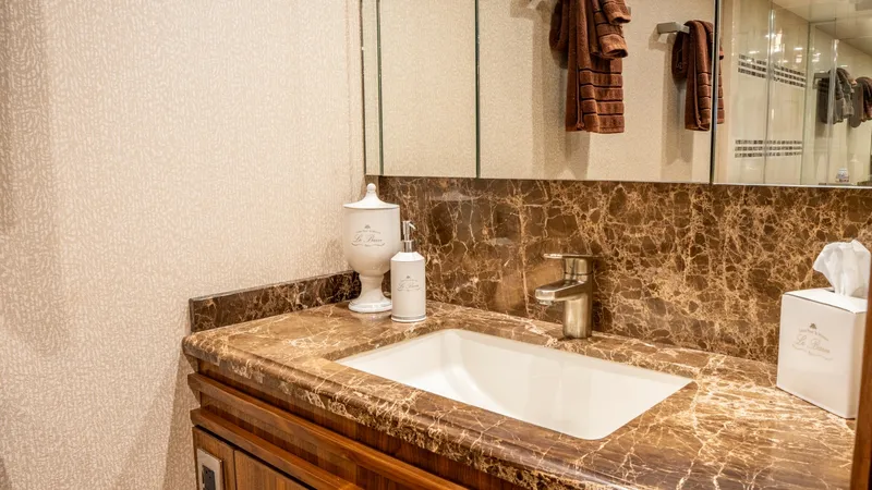 Slide: The Image of Luxurious Bathroom Vanity Area This elegant bathroom on the Viking 92 Skybridge features a stunning marble vanity with a sleek, integrated sink. The rich wood cabinetry adds warmth and sophistication, while the mirrored wall enhances the sense of space and light. High-end fixtures and - 6612541