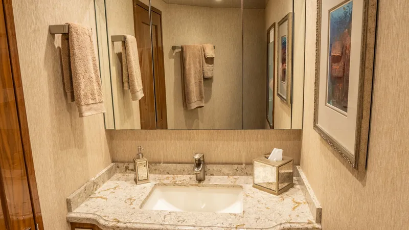 Slide: The Image of Elegant Guest Bathroom Vanity This guest bathroom on the Viking 92 Skybridge showcases a sleek vanity with a polished marble countertop, enhancing the luxurious feel. The mirrored cabinet provides ample storage, while the warm wood finish adds a touch of elegance. Thoughtful details l - 6612521