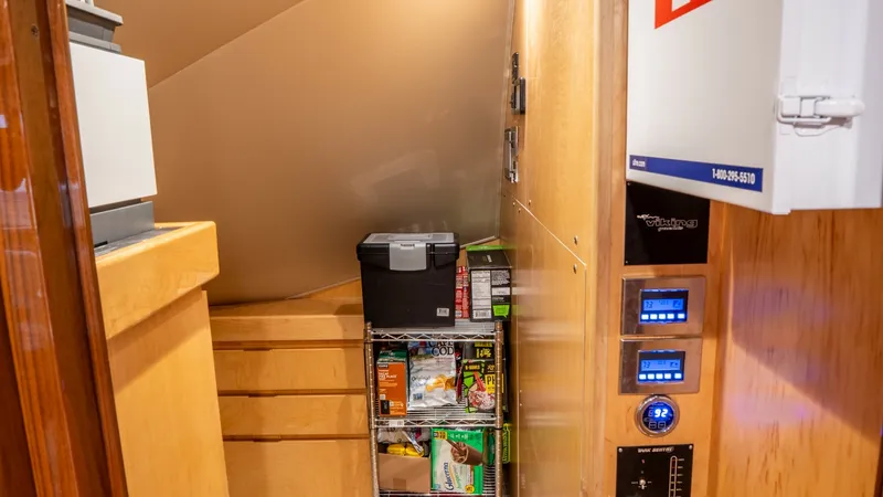 Slide: The Image of Utility Storage and Control Panel This space on the Viking 92 Skybridge features a neatly organized utility storage area with wooden cabinetry and shelving for easy access to supplies. The adjacent wall hosts an intuitive control panel, providing essential monitoring and management functi - 6612546