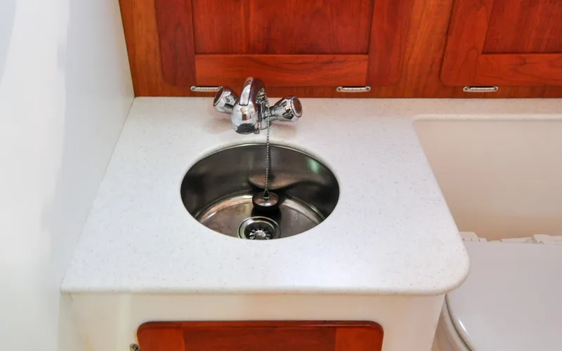 Slide: The Image of Hunt Surfhunter 29 - Judith Ann 2005 Hunt Yachts Surfhunter 29 bathroom sink with chrome faucet and wooden cabinetry. - 6302520