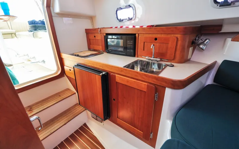 Slide: The Image of Hunt Surfhunter 29 - Judith Ann 2005 Hunt Yachts Surfhunter 29 interior with kitchenette, featuring wood cabinetry and compact appliances. - 6302485