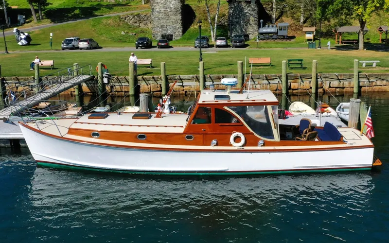 Slide: The Image of 1958 Bunker and Ellis 42 | Aleria Classic 1958 Bunker and Ellis 42 boat docked at a scenic waterfront. - 6307408