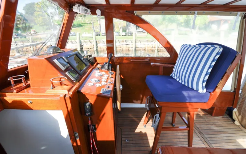 Slide: The Image of 1958 Bunker and Ellis 42 | Aleria 1958 Bunker and Ellis 42 boat interior with wooden helm and striped cushion. - 6307493