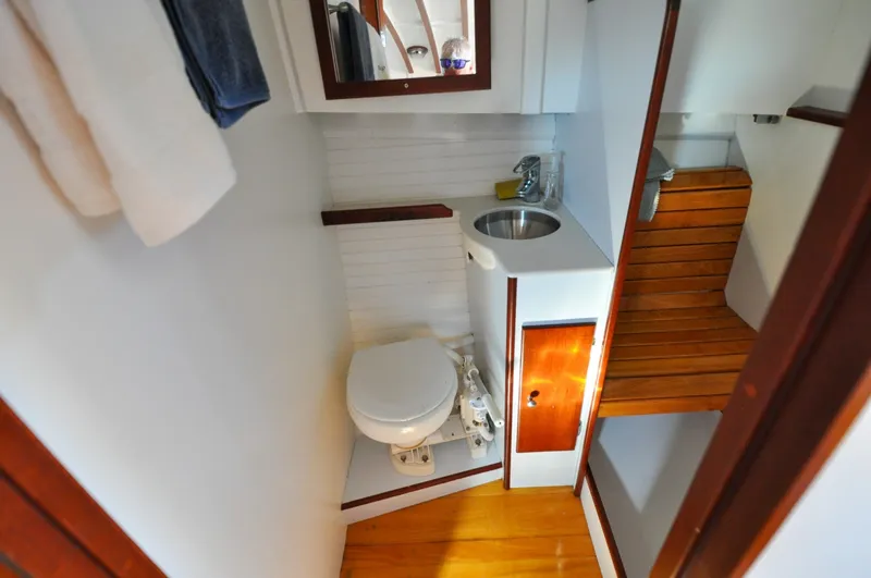 Slide: The Image of 1958 Bunker and Ellis 42 | Aleria Compact bathroom in a 1958 Bunker and Ellis 42 boat, featuring toilet and sink. - 6307443
