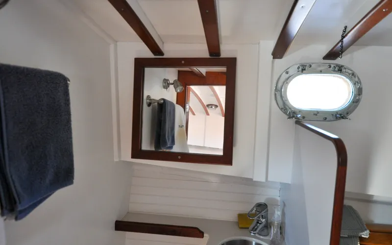 Slide: The Image of 1958 Bunker and Ellis 42 | Aleria Interior of 1958 Bunker and Ellis 42 boat, featuring a mirror, porthole, and wooden accents. - 6307500