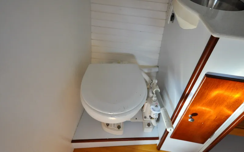 Slide: The Image of 1958 Bunker and Ellis 42 | Aleria 1958 Bunker and Ellis 42 boat bathroom with white toilet and wooden cabinet. - 6307459