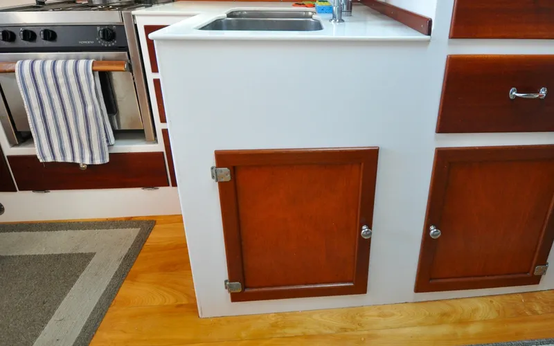 Slide: The Image of 1958 Bunker and Ellis 42 | Aleria 1958 Bunker and Ellis 42 boat kitchen with wooden cabinets and stainless steel sink. - 6307518