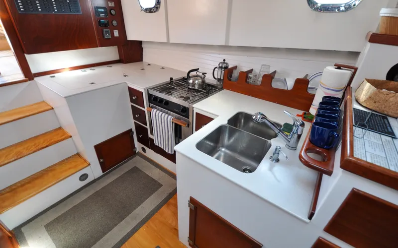 Slide: The Image of 1958 Bunker and Ellis 42 | Aleria 1958 Bunker and Ellis 42 yacht kitchen with stove, sink, and wooden cabinetry. - 6307453