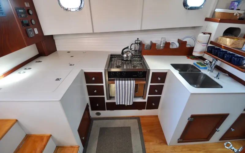 Slide: The Image of 1958 Bunker and Ellis 42 | Aleria Vintage 1958 Bunker and Ellis 42 yacht kitchen with stove, sink, and wooden cabinetry. - 6307523