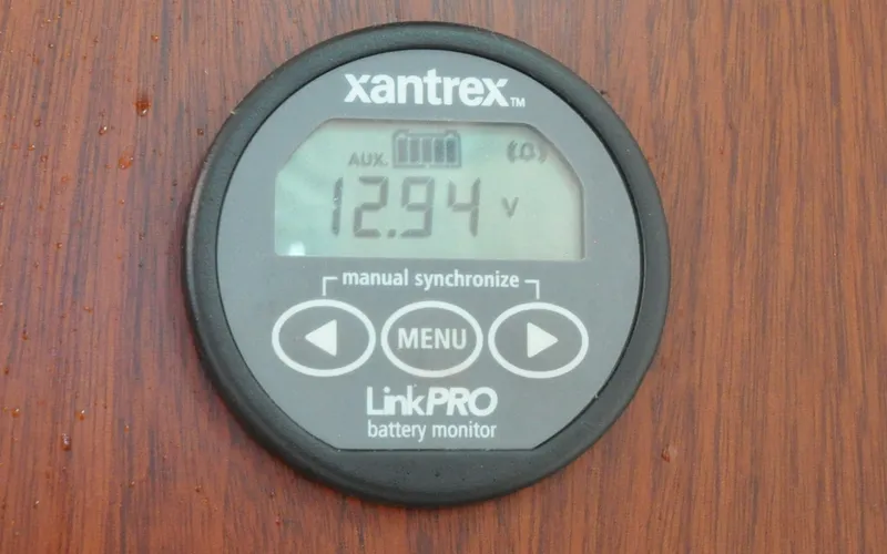 Slide: The Image of 1958 Bunker and Ellis 42 | Aleria Xantrex LinkPRO battery monitor displaying 12.94 volts on a wooden panel. - 6307536