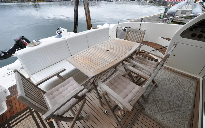 Slide: The Image of 1996 Azimut 54 | Calmati 1996 Azimut Cinquantaquattro yacht deck with wooden dining table and cushioned chairs. - 6308857