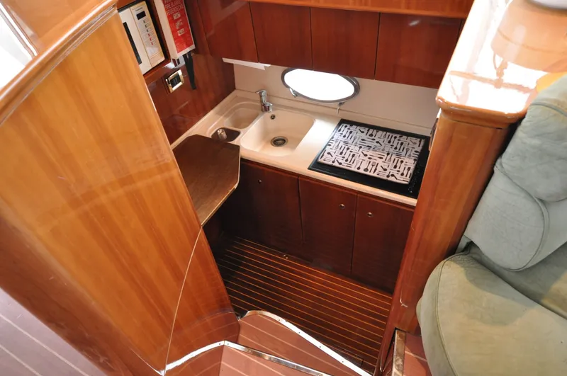 Slide: The Image of 1996 Azimut 54 | Calmati Compact kitchen area in a 1996 Azimut Cinquantaquattro yacht with wooden cabinetry. - 6308621