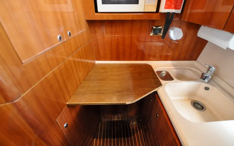 Slide: The Image of 1996 Azimut 54 | Calmati 1996 Azimut Cinquantaquattro yacht kitchen with wooden cabinetry and compact sink area. - 6308995