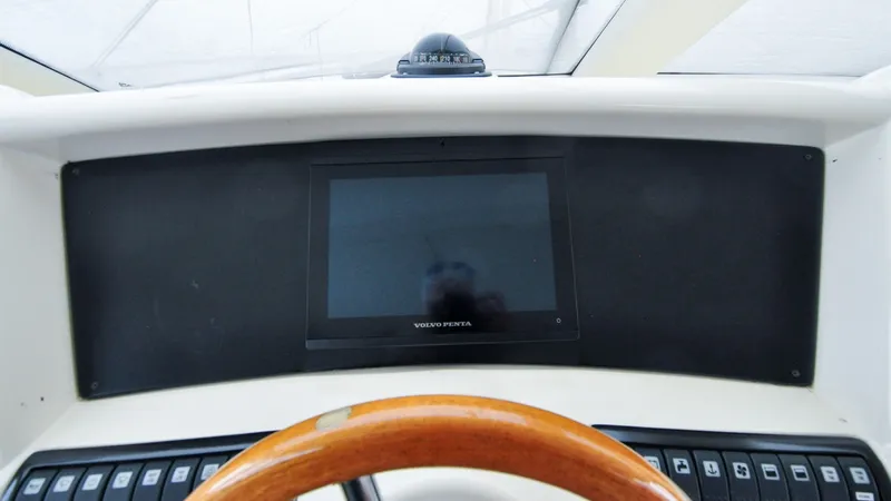Slide: The Image of 1996 Azimut 54 | Calmati Dashboard of a 1996 Azimut 54 yacht with Volvo Penta display and wooden steering wheel. - 6308992
