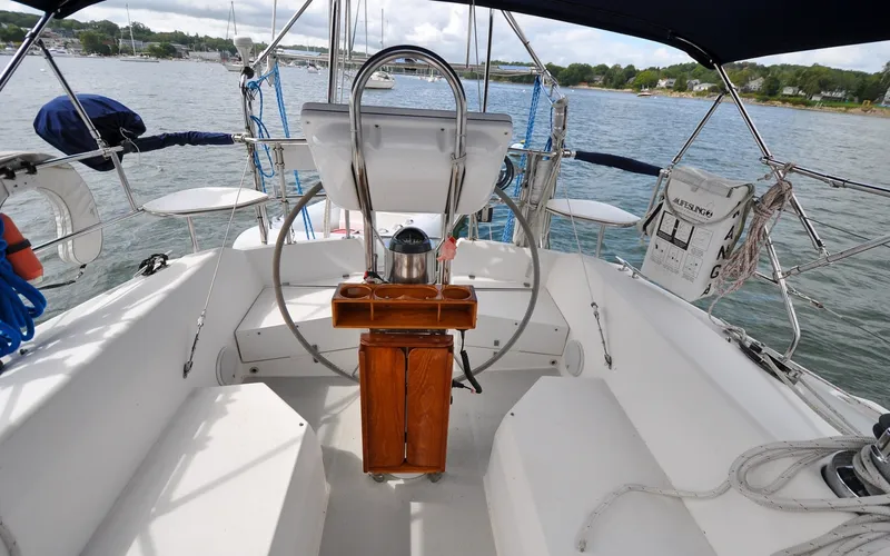 Slide: The Image of 1993 Catalina 42 | Kanga Cockpit of a 1993 Catalina 42 sailboat with steering wheel and seating, docked by the water. - 6318893