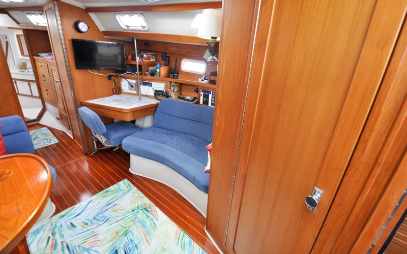 Slide: The Image of 1993 Catalina 42 | Kanga Interior of 1993 Catalina 42 sailboat with blue seating, navigation desk, and wooden finishes. - 6318905