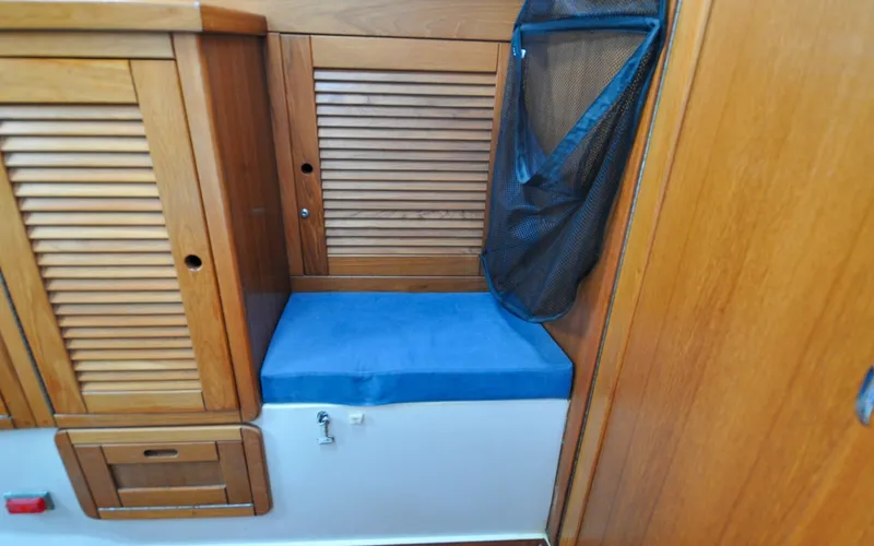 Slide: The Image of 1993 Catalina 42 | Kanga Wooden interior of 1993 Catalina 42 sailboat with blue cushioned seat and storage. - 6318897