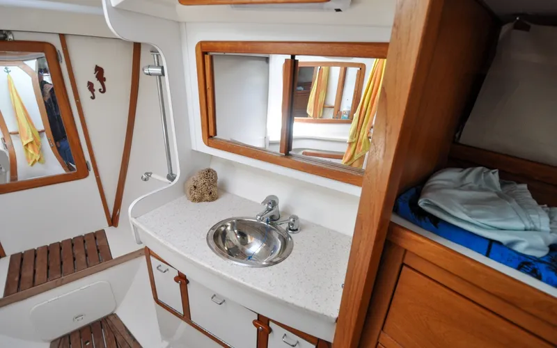 Slide: The Image of 1993 Catalina 42 | Kanga 1993 Catalina 42 yacht bathroom with sink, mirror, and wooden cabinetry. - 6318902