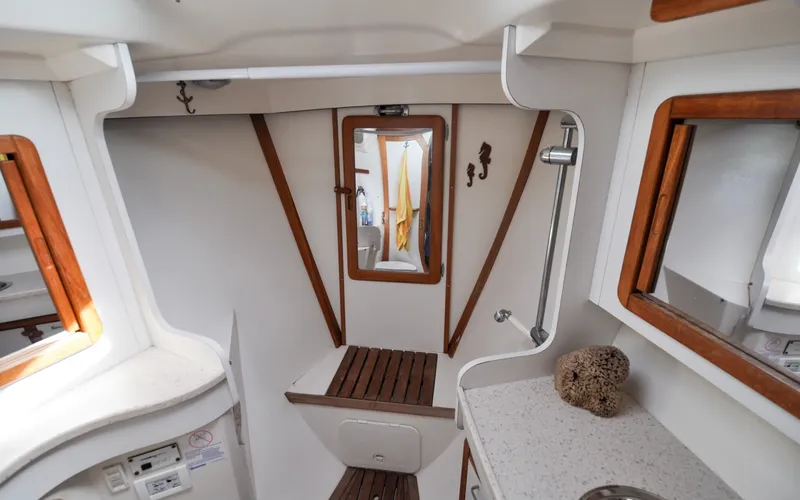 Slide: The Image of 1993 Catalina 42 | Kanga Interior of a 1993 Catalina 42 sailboat, featuring a compact bathroom with wooden accents. - 6318903