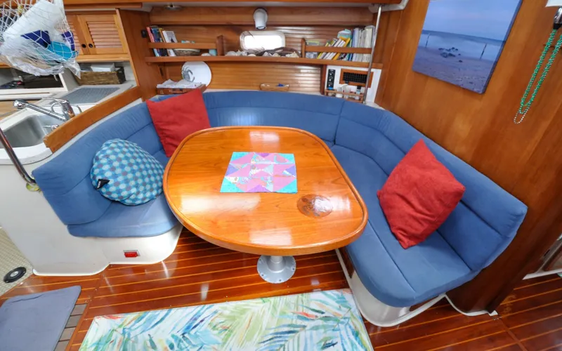 Slide: The Image of 1993 Catalina 42 | Kanga 1993 Catalina 42 yacht interior with blue seating, wooden table, and nautical decor. - 6318921