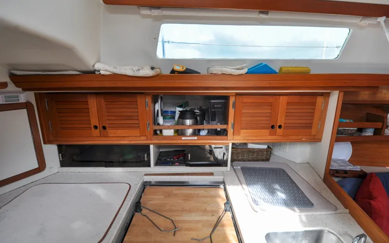 Slide: The Image of 1993 Catalina 42 | Kanga Interior of a 1993 Catalina 42 sailboat kitchen with wooden cabinets and countertop. - 6318929