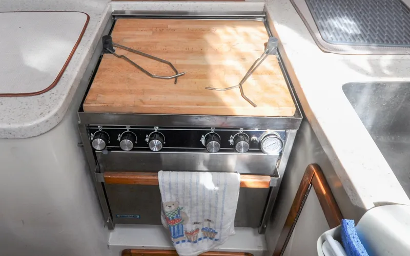 Slide: The Image of 1993 Catalina 42 | Kanga 1993 Catalina 42 yacht kitchen with stove, wooden countertop, and towel. - 6318928