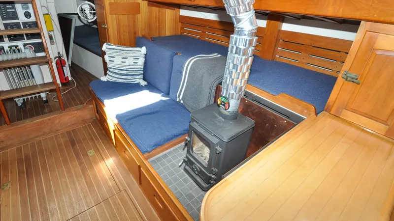 Slide: The Image of 1987 Wittholtz/Luzier 49 | Destiny Cozy interior of 1987 Custom Wittholtz/Luzier Sloop/Cutter with wood stove and blue seating. - 6319039