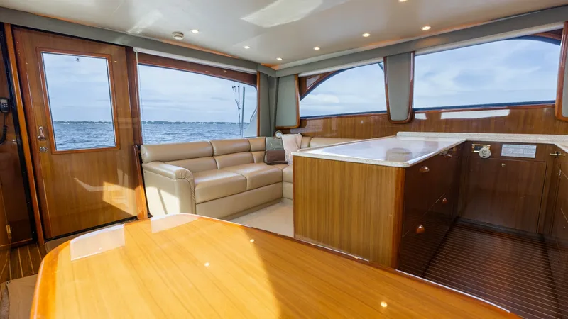 Slide: The Image of Main Salon with Ocean View The main salon of the 2007 Viking 45 Convertible 'Desperado' offers a spacious and inviting atmosphere, highlighted by panoramic windows providing stunning ocean views. The plush L-shaped sofa complements the polished wood finishes and the elegant cabinet - 6394727