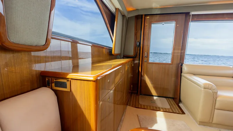 Slide: The Image of Salon Entryway with Ocean View This inviting salon entryway on the 2007 Viking 45 Convertible 'Desperado' showcases stunning wood finishes and a panoramic ocean view. The warm tones of the cabinetry complement the plush seating, offering a welcoming and luxurious atmosphere. Large wind - 6394729