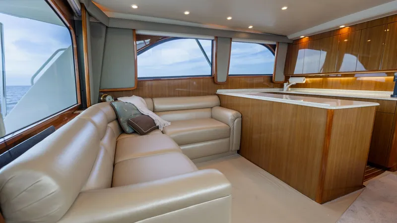 Slide: The Image of Spacious Salon with Leather Seating This inviting salon on the 2007 Viking 45 Convertible, 'Desperado,' features plush leather seating perfect for relaxation. Surrounded by large windows, the space is filled with natural light, enhancing the warm wood cabinetry and sleek countertops. Ideal - 6394731