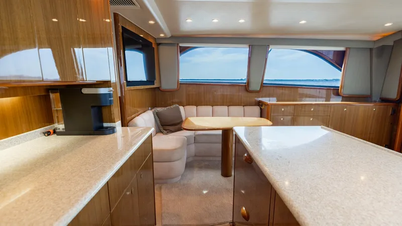Slide: The Image of Spacious Salon with Galley and Views This inviting salon on the 2007 Viking 45 Convertible features elegant wood finishes and ample natural light from large windows. The plush L-shaped sofa provides comfort, complemented by a stylish wooden table, perfect for dining or relaxation. The adjace - 6394734