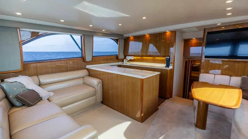 Slide: The Image of Spacious Salon with Galley View This inviting salon on the 2007 Viking 45 Convertible exudes luxury with its plush leather seating and warm wood finishes. The open layout features a well-appointed galley with elegant countertops, perfect for entertaining. Large windows offer panoramic o - 6394718