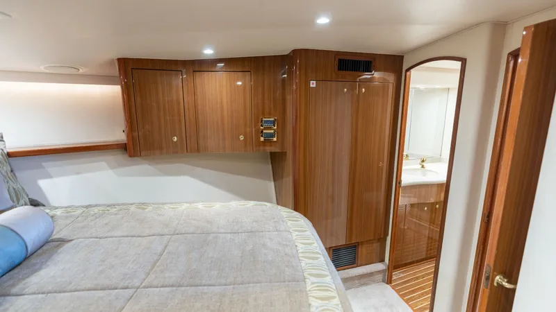 Slide: The Image of Forward Stateroom with Ensuite The forward stateroom offers a cozy retreat with its plush bedding and elegant wood cabinetry. Ample storage is provided by built-in cabinets, and the ensuite bathroom features fine fixtures and a sleek design. Soft lighting creates a warm and inviting at - 6394737