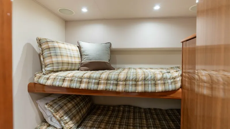Slide: The Image of Cozy Twin Cabin with Bunks This inviting twin cabin features neatly arranged bunk beds with plaid bedding, offering a comfortable resting space for guests. Recessed lighting overhead provides a warm ambiance, while the wood finishes add a touch of elegance. Ideal for relaxation, th - 6394744