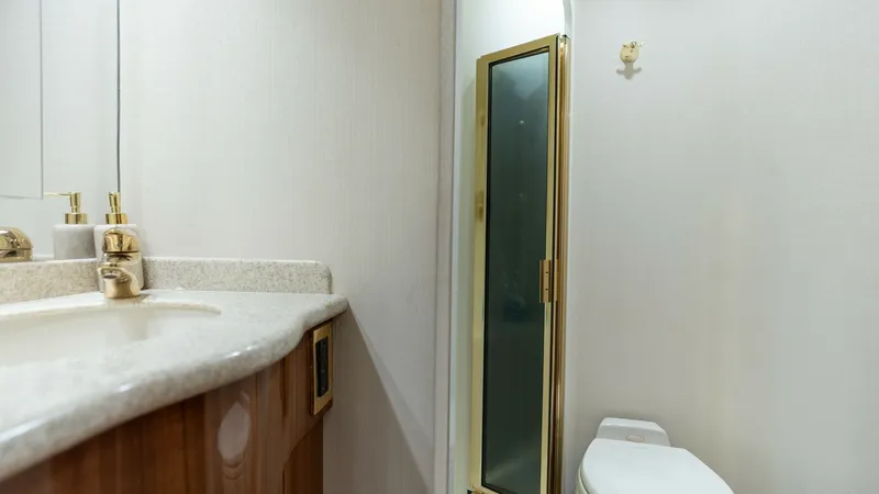 Slide: The Image of Compact Yacht Bathroom with Shower This well-appointed bathroom on the 2007 Viking 45 Convertible features a sleek vanity with a polished countertop and stylish fixtures. The compact layout maximizes space efficiency, offering a private shower with a frosted glass door for added elegance. - 6394745